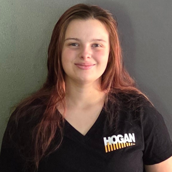 Young woman smiling in a black Hogan t-shirt against a gray background.