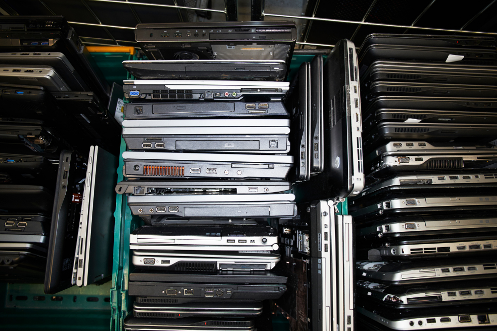 Stacks of old laptops piled together for secure recycling and data protection.